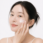 Woman applying cream to her face with a white background