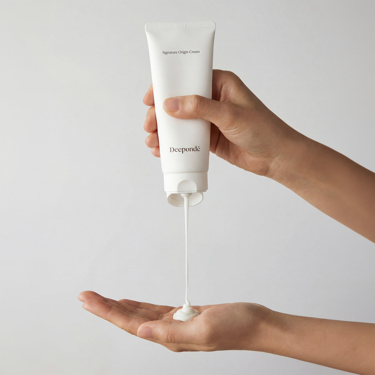 Deepondé Signature Origin Cream texture shot — lightweight white cream dispensed from tube